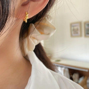 Gros plan de boucles d'oreilles créoles torsadées dorées portées sur un mannequin