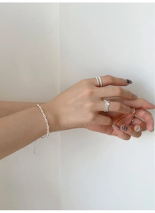 Vista macro di anelli irregolari in argento S925 e bracciale con trama a corda ritorta