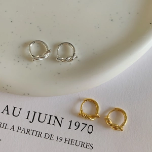 Vue détaillée de boucles d'oreilles nœuds dorées et argentées sur un plateau
