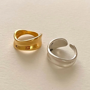 Detailed view of silver and gold irregular wavy open rings on a textured background