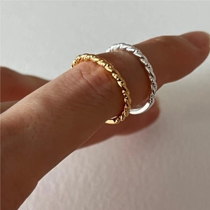 Macro di anelli minimalisti intrecciati color oro e argento indossati sulle dita