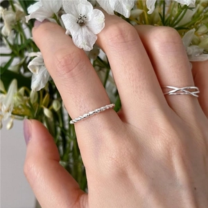 Dettaglio dell'anello in argento intrecciato e della fascia minimalista a X sulla mano