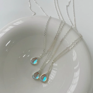 Three minimalist 925 sterling silver drop necklaces with iridescent opal pendants in a bowl