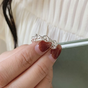 Close-up of a silver multi-layered woven band ring with a polished metallic finish