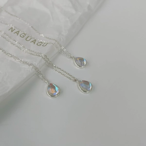 Macro detail of three silver waterdrop necklaces with iridescent aurora crystal pendants