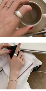 Detailed view of wide matte brushed silver ring with elegant twist band and pearl bracelet