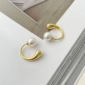 Macro detail of S925 hallmark on golden C-shaped pearl earrings with water drop design