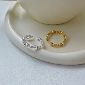 Close-up of twisted chain open rings in gold and silver finish on ceramic plate