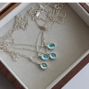 Detail of 925 sterling silver necklaces with shimmering teardrop opal pendants on velvet