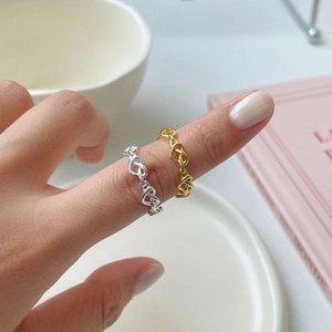 Detail shot of hollow heart link rings in silver and gold on a model's finger