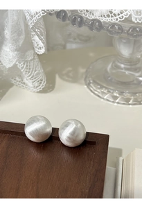 Detail of S925 sterling silver ball earrings with elegant brushed metal texture on wood