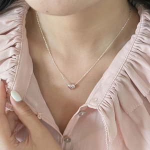 Gros plan d'un collier avec pendentif coeur en argent S925 porté au cou pour femmes