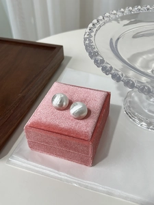 Detail view of silver brushed ball stud earrings placed on a pink velvet jewelry box lid