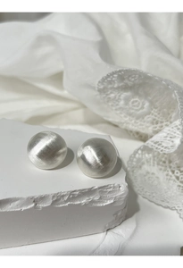 Close-up of matte brushed silver ball earrings on white stone with lace background