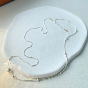 Minimalist silver double-layered necklace featuring sleek snake and bead chain designs