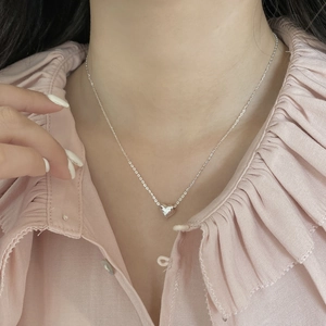 Gros plan d'un collier avec pendentif cœur en argent S925 minimaliste sur une femme