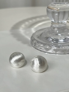 Detail of minimalist S925 silver sphere earrings with a textured brushed metal finish