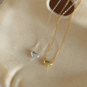 Détail de colliers avec pendentif cœur en argent et or sur un plateau en céramique