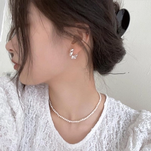 Élégantes créoles argentées irrégulières et collier de perles blanches sur mannequin femme