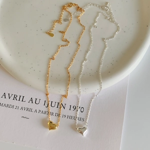 Détail de colliers cœur minimalistes en argent 925 doré et argenté sur plat en céramique