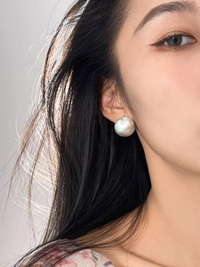 Close-up of minimalist brushed silver spherical earring worn by a model in profile view