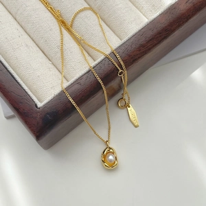 Macro detail of 925 silver pearl pea pendant necklace with organic lava design gold finish