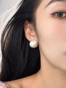 Close-up of minimalist large round pearl stud earring worn by model for an elegant look
