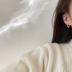 Close-up of a 925 sterling silver twisted rope hoop earring worn on a model's ear