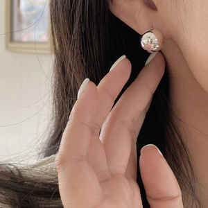 Close-up of minimalist 925 sterling silver ball stud earrings worn on the earlobe