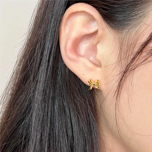Boucles d'oreilles nœud en argent 925 doré portées par un mannequin pour style épuré