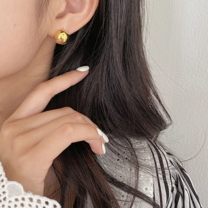Close-up of minimalist gold ball stud earrings with a polished mirror finish on ear