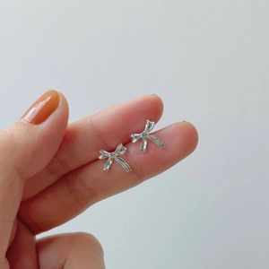 Gros plan de boucles d'oreilles nœud en argent 925 montrant la taille réelle sur la main