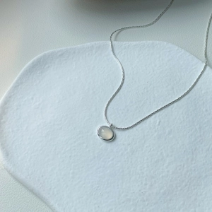 Minimalist s925 silver necklace with an oval chalcedony pendant on a white stone tray