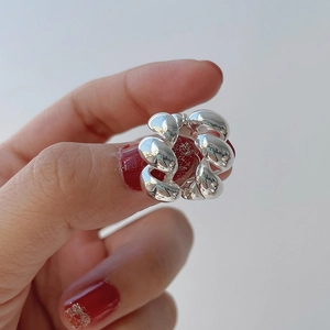 Boucle d'oreille torsadée en argent sterling S925 poli présentée sur main sur fond gris