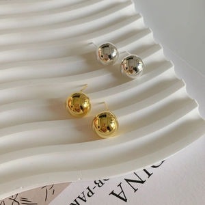 Detailed macro view of high-polished gold and silver sphere stud earrings on white display