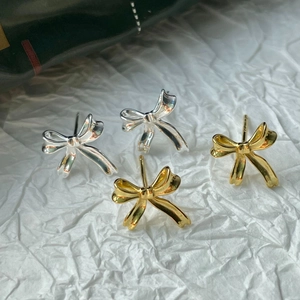 Détail macro de boucles d'oreilles nœud papillon en argent 925 doré et argenté poli