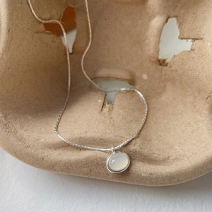 Macro view of oval white chalcedony pendant on S925 sterling silver chain necklace