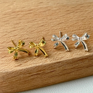 Vue détaillée de boucles d'oreilles ruban en argent et or sur fond de bois naturel