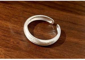 Macro shot of minimalist 925 sterling silver ring with brushed matte finish on wood surface