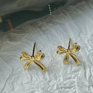 Vue détaillée de boucles d'oreilles nœud en argent 925 doré sur papier froissé