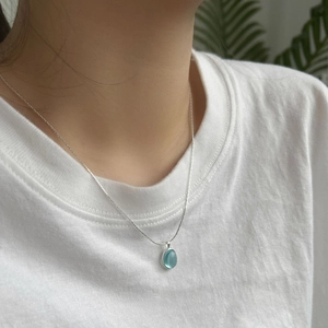 Close-up of minimalist S925 silver necklace with blue oval gemstone pendant on model