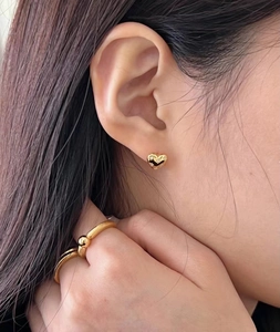 Close-up of elegant S925 silver heart stud earrings and gold bead ring on female model