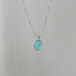 Detailed view of an oval blue gemstone pendant on a polished silver snake chain