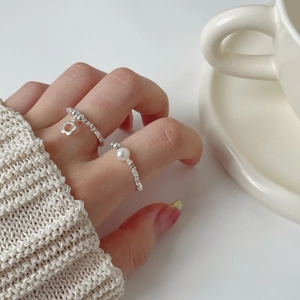 S925 silver rings set with a flower pendant and a pearl on a model's hand