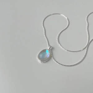 Close-up of oval moonstone pendant on silver snake chain with blue-purple sheen