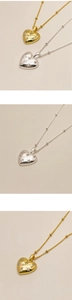 Macro detail of gold and silver heart pendants with sparkling cubic zirconia inlay