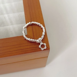 Close-up of S925 silver beaded ring with hollow flower pendant on wooden box