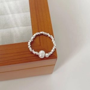 Detailed view of 925 silver beaded ring with white pearl on a wooden jewelry organizer
