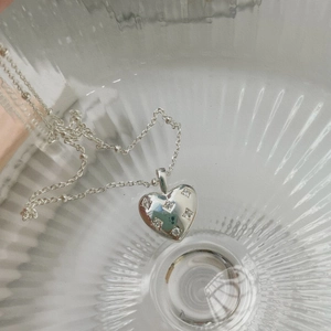 Macro detail of silver heart pendant with sparkling cubic zirconia on glass surface