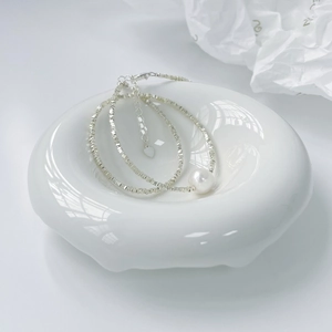 Dettaglio della collana in argento S925 con perla bianca rotonda su un vassoio di ceramica